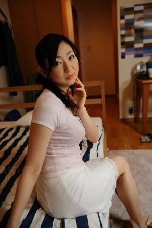 Slender mature Japanese woman Emiko Koike bends over to pose in white dress - Japan on picsfans.one